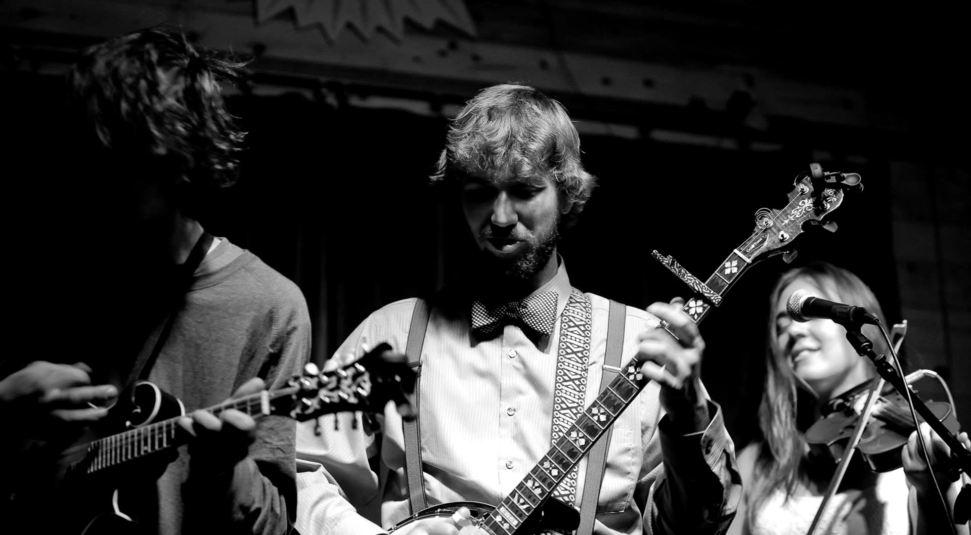 Tyler Rice on banjo with mandolin and fiddle players beside him