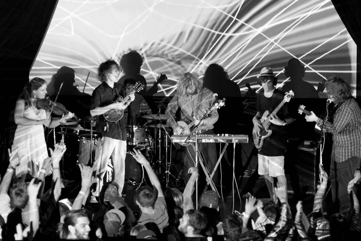Tyler Rice playing banjo over a keyboard in front of a psychedelic projection