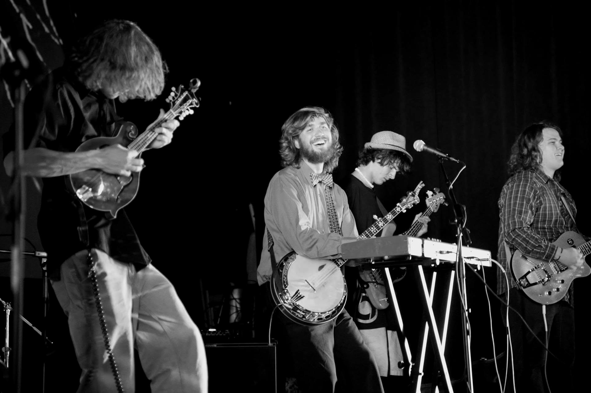 Full band under green laser lights with the crowd's hands raised, black and white