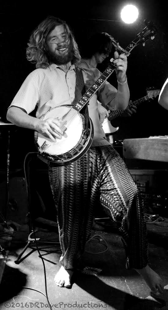 Tyler Rice playing banjo barefoot in patterned pants