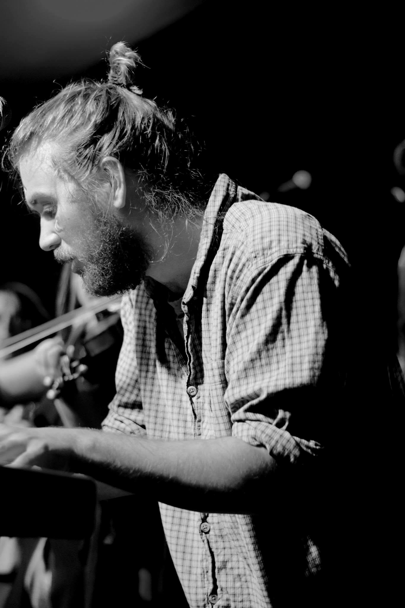 Profile of Tyler Rice at the keys with a man bun