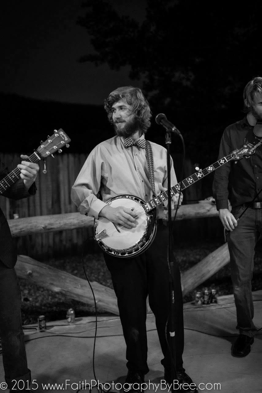 Tyler Rice playing banjo outdoors at night in a gingham bow tie